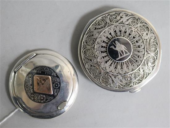 Two middle eastern white metal and niello compacts, one with filligree cover, largest 75mm.